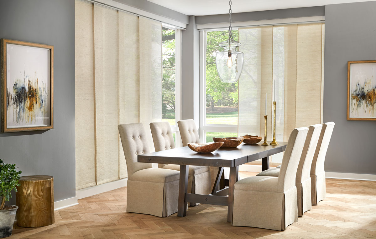 Modern living room with dining set and large window shades covering windows.